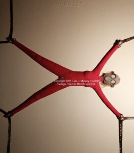 tactile cordage by Lisa J. Murphy. A naked woman wearing a gas mask with her limbs tied to points out of view.